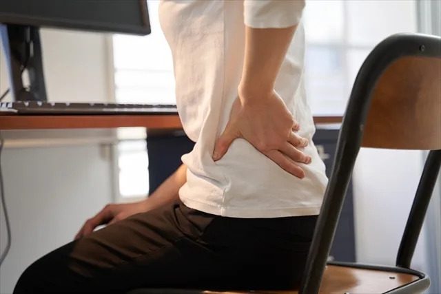 デスクワークによる慢性腰痛のイメージ（仮画像）